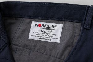 Satin woven clothing label sewn inside work pants for industrial uniforms showing smooth finish and clear detail