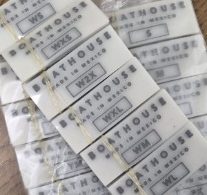 Stacks of custom heat transfer labels printed with “Boathouse Made in Mexico,” showing clear sizing options and professional production quality.